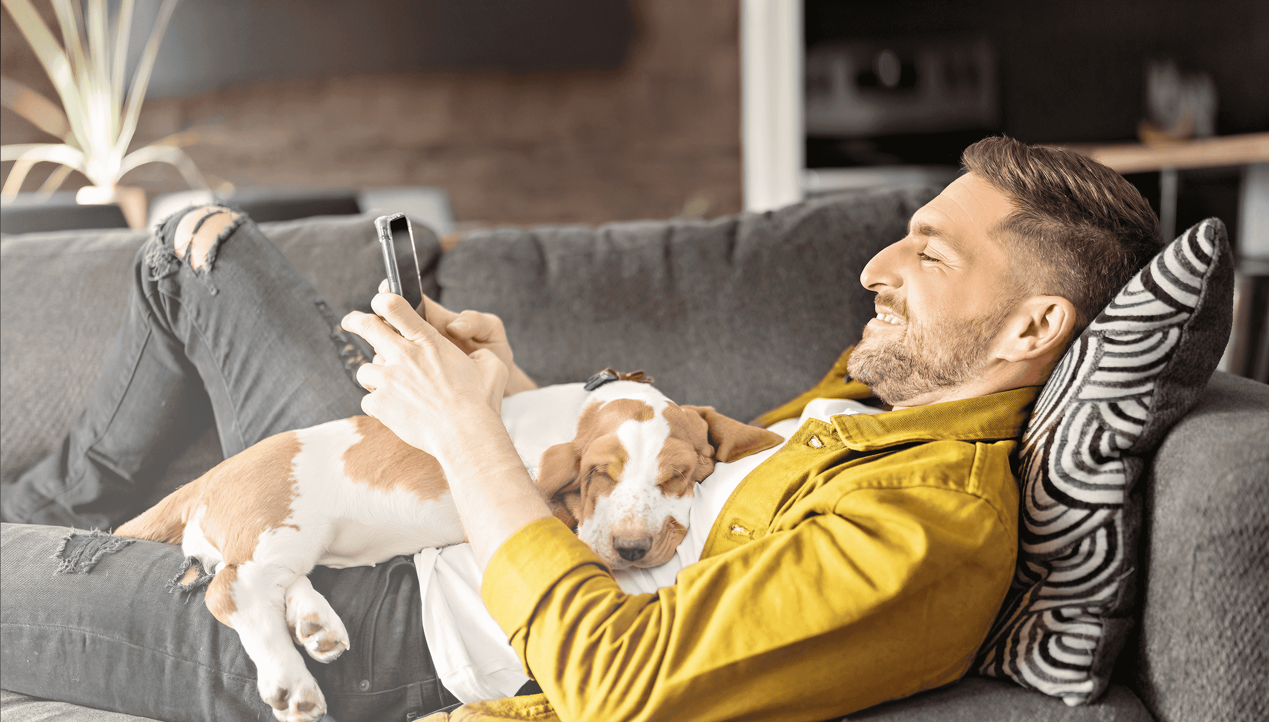 Man lying on couch with a dog and his phone, thinking about Brite Payments and the best Giropay alternative.